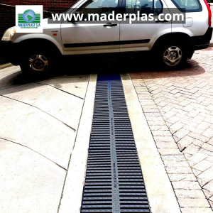 Rejilla plástica lineal de polipropileno Maderplast instalada en un canal de drenaje vehicular, soportando el paso de un automóvil en el acceso a un parqueadero.