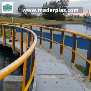 Barandas plásticas anticorrosivas Maderplast instaladas en una pasarela curva de una planta de tratamiento de agua, diseñadas para brindar seguridad y resistencia en ambientes industriales.