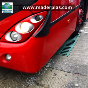 Bus articulado circulando sobre una rejilla plástica para sumidero Maderplast de polipropileno, diseñada para soportar tráfico vehicular pesado en vías urbanas.