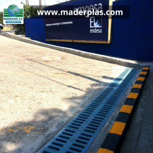 Rejilla plástica de polipropileno Maderplast instalada en un canal de drenaje vehicular para la evacuación de aguas lluvias en una vía de acceso industrial.