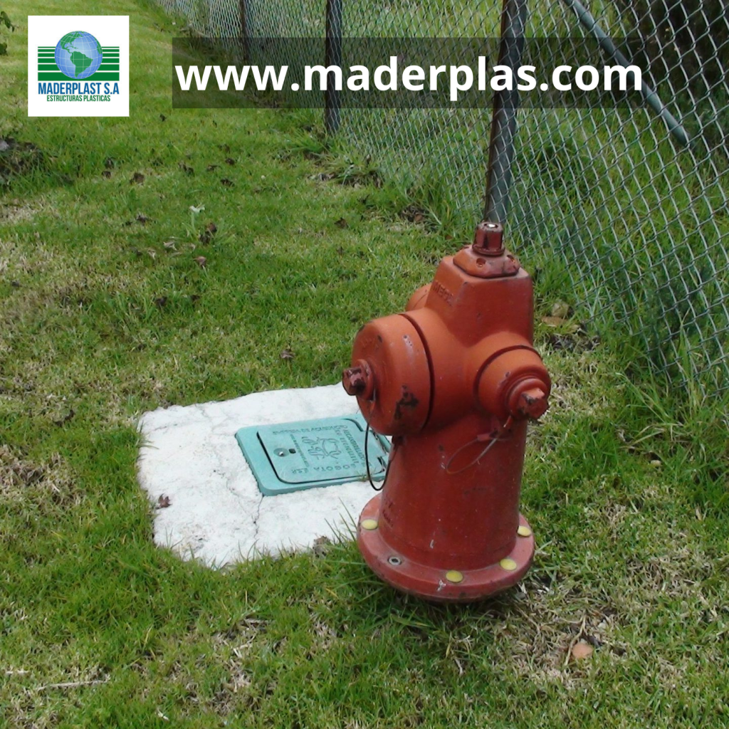 Tapa plástica para válvula totalizadora de acueducto Maderplast instalada junto a un hidrante en una red de distribución de agua potable.