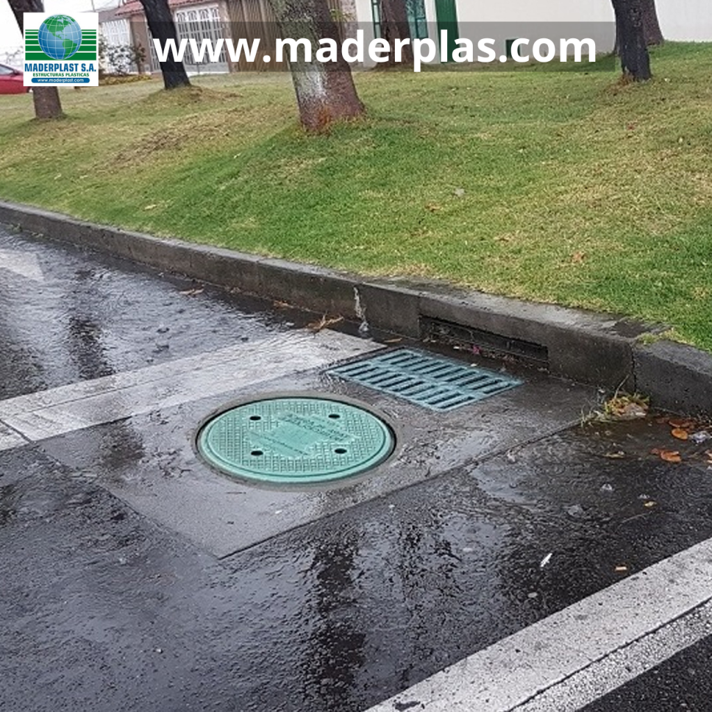 Tapa de alcantarilla plástica Maderplast instalada en un pozo de inspección sobre una vía urbana, resistente a la humedad, la corrosión y las condiciones de intemperie.