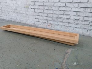 Rejilla rectangular plástica de ventilación o drenaje color beige sobre piso de concreto