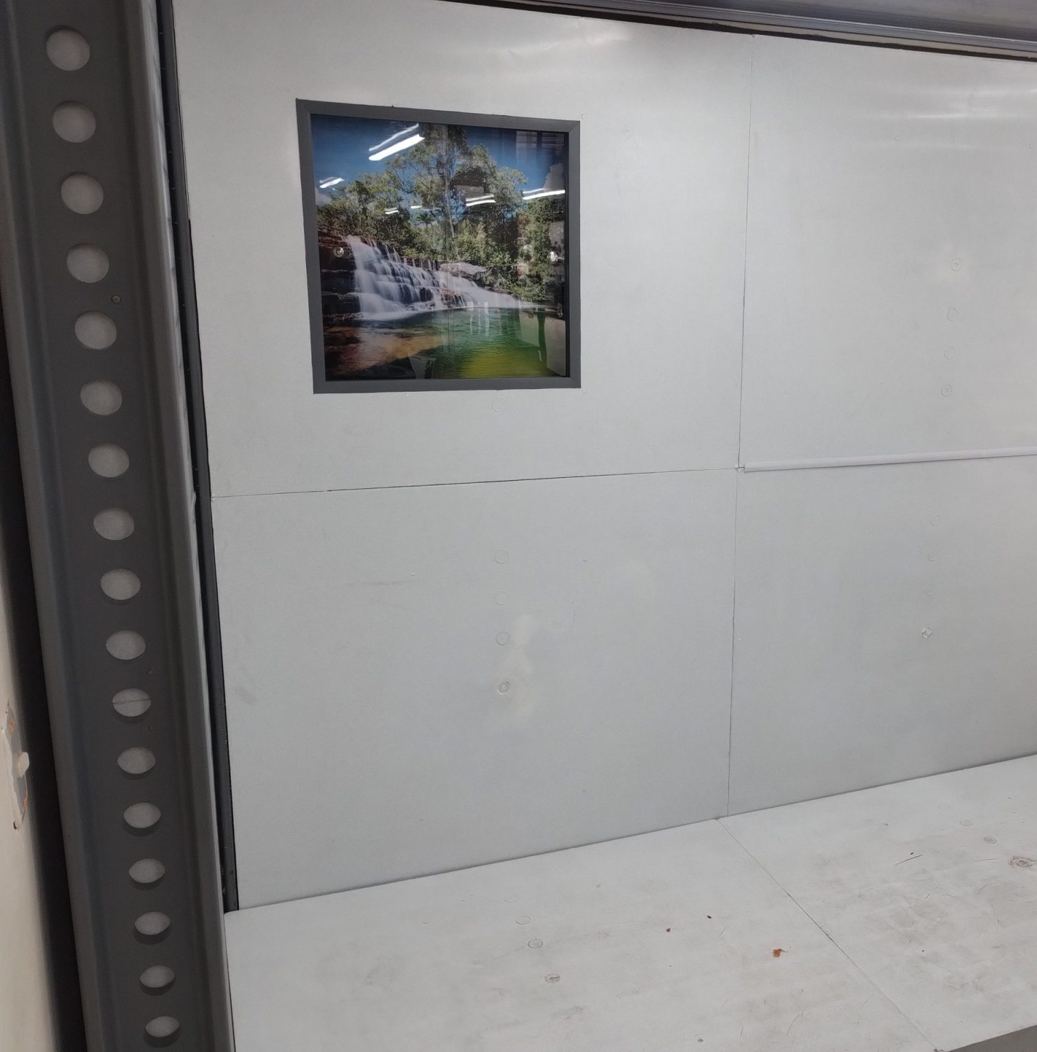 Vista completa de módulo de pared y piso para campamento en polipropileno Maderplast, superficie blanca, instalación modular resistente y decoración interior con imagen de paisaje natural.